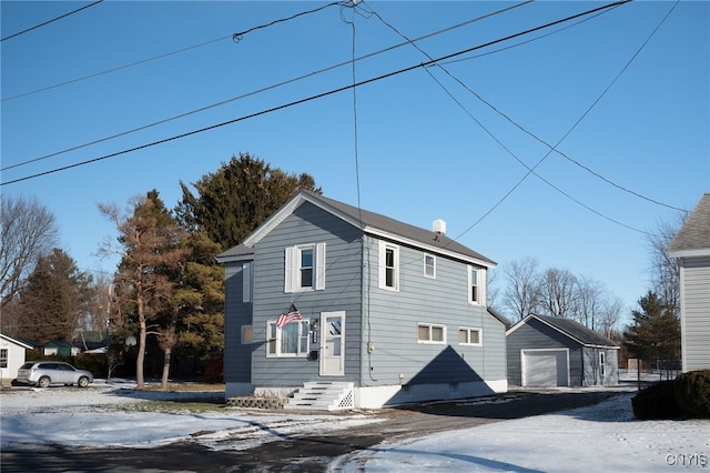 view of snow covered exterior with a garage and an outbuilding