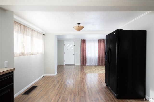 interior space with black fridge with ice dispenser and hardwood / wood-style flooring