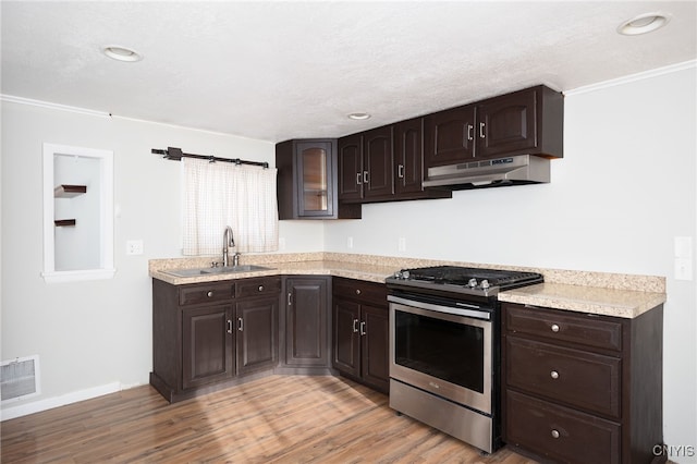 kitchen with sink, stainless steel gas range oven, crown molding, dark brown cabinets, and light wood-type flooring