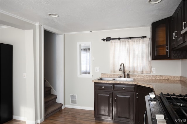 kitchen with dark brown cabinets, a textured ceiling, sink, black gas stove, and dark hardwood / wood-style floors