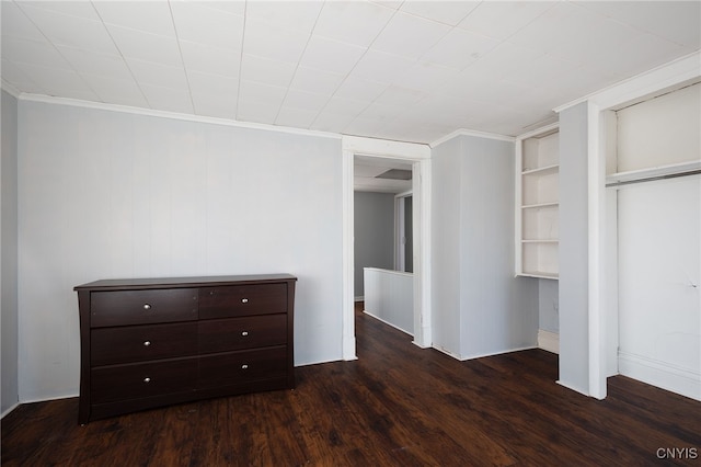 unfurnished bedroom with dark hardwood / wood-style flooring, crown molding, and a closet