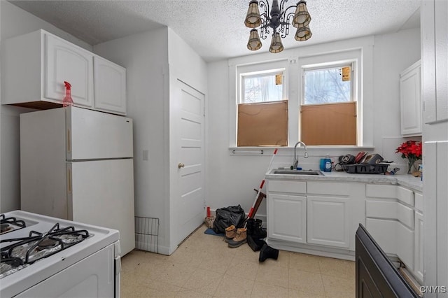 kitchen with sink, white cabinets, white appliances, and an inviting chandelier