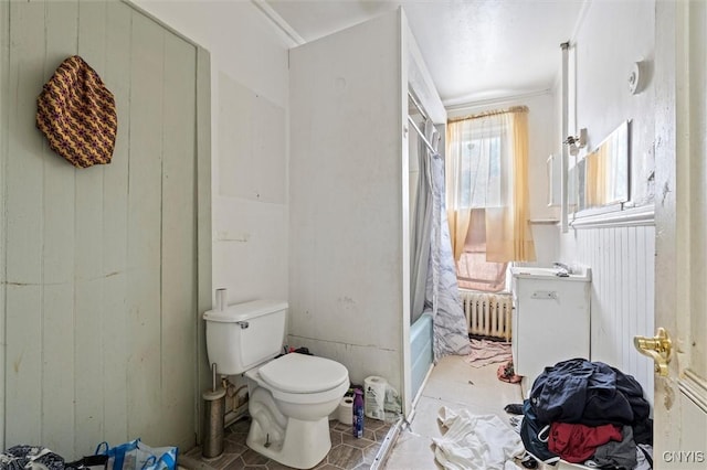 bathroom with shower / bath combo, wood walls, toilet, and radiator