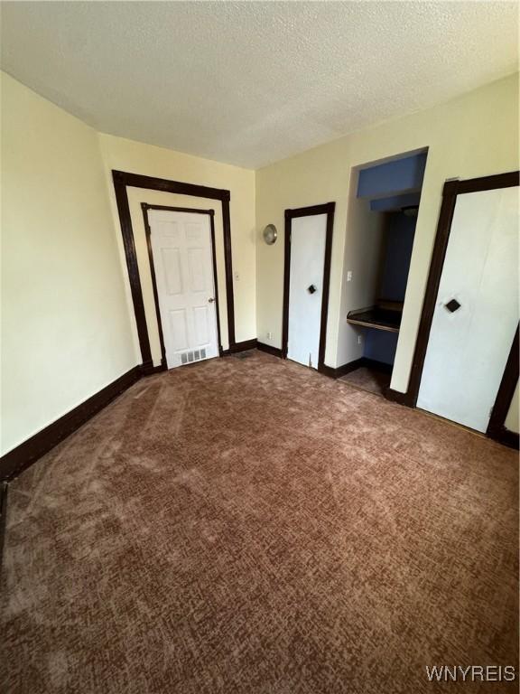 unfurnished bedroom with dark carpet and a textured ceiling