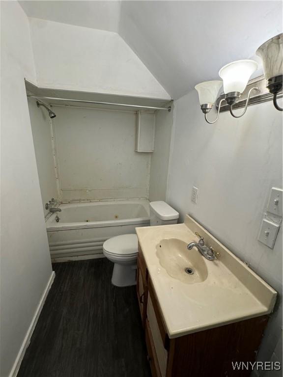 bathroom with hardwood / wood-style flooring, vanity, vaulted ceiling, and toilet