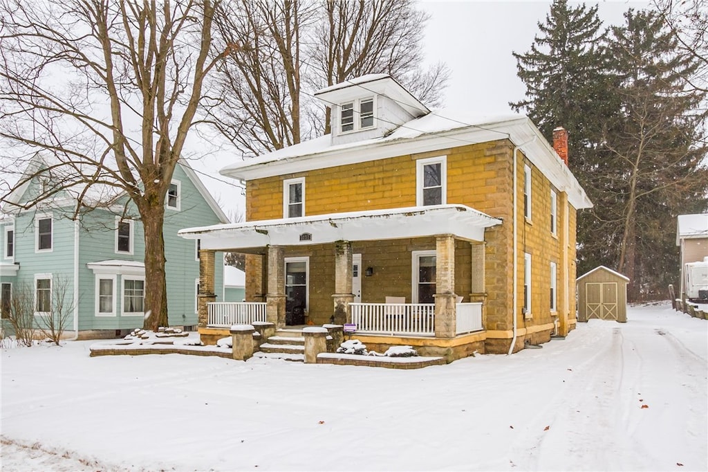 view of front of home featuring covered porch and a storage shed