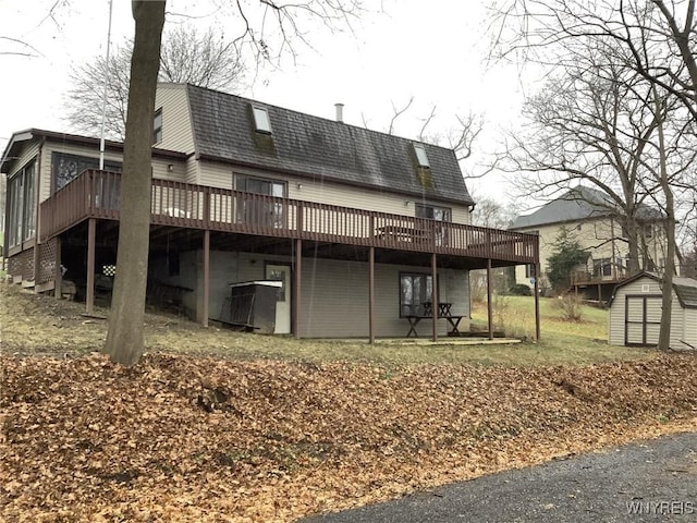 back of property with a deck and a storage shed