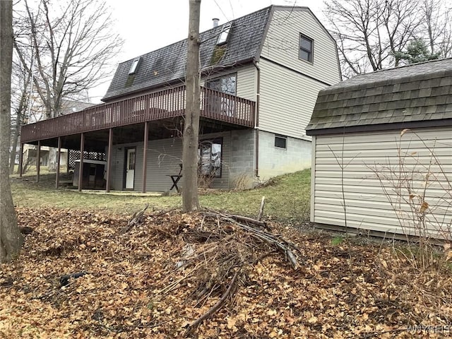 rear view of house featuring a wooden deck and a storage shed