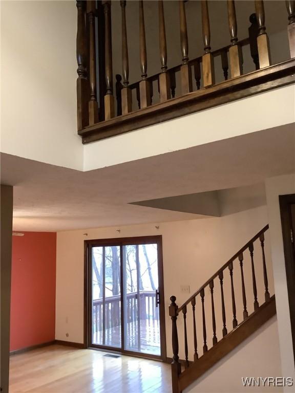 staircase with a towering ceiling and wood-type flooring