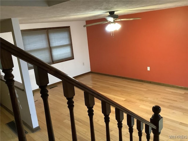 stairway featuring ceiling fan and hardwood / wood-style flooring