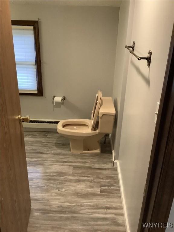 bathroom with toilet, hardwood / wood-style floors, and a baseboard heating unit