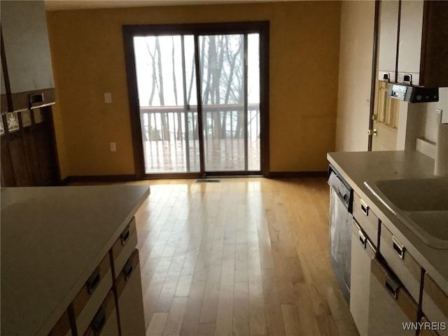 kitchen featuring dishwasher, white cabinetry, sink, and light hardwood / wood-style flooring