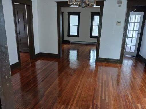 interior space with baseboard heating, dark wood-type flooring, and an inviting chandelier