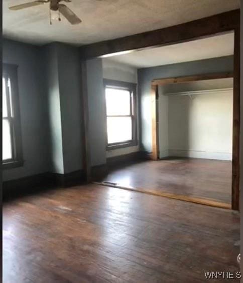 spare room featuring ceiling fan, dark hardwood / wood-style floors, and beam ceiling