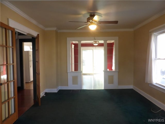 carpeted spare room featuring a wealth of natural light, ceiling fan, and ornamental molding