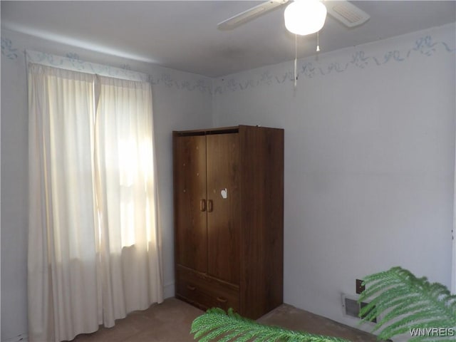 carpeted bedroom featuring multiple windows and ceiling fan