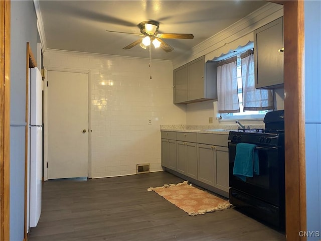 kitchen with sink, dark hardwood / wood-style floors, gray cabinets, black gas range oven, and white fridge