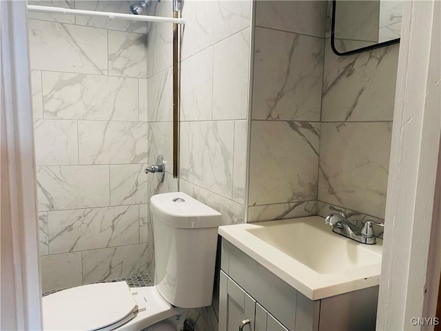 bathroom with vanity, toilet, and tile walls