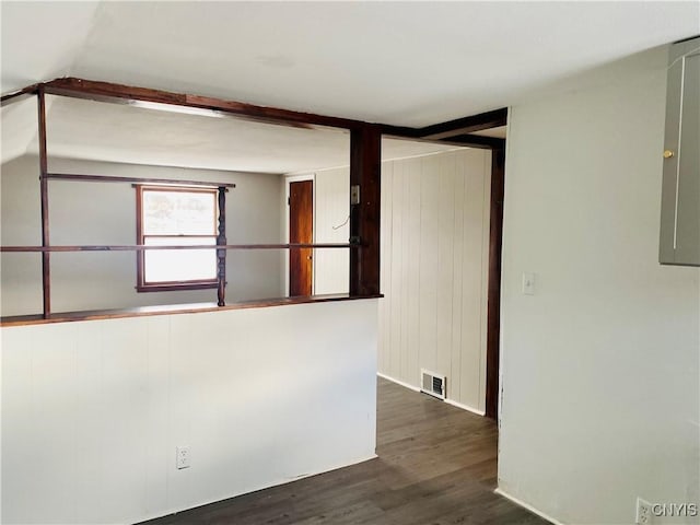 unfurnished room with beam ceiling, electric panel, and dark wood-type flooring