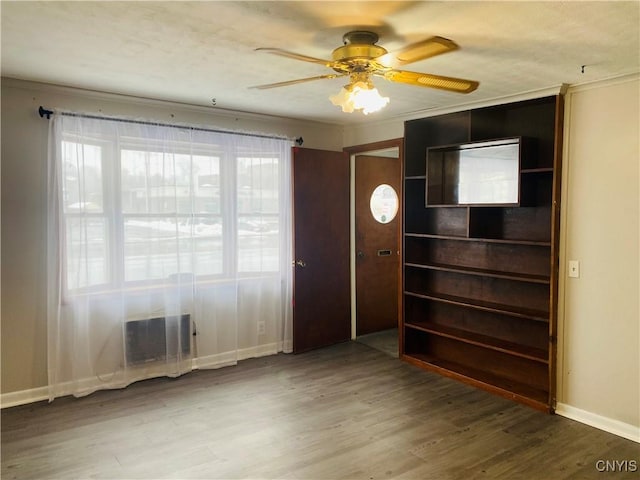 interior space featuring multiple windows, wood-type flooring, ceiling fan, and crown molding