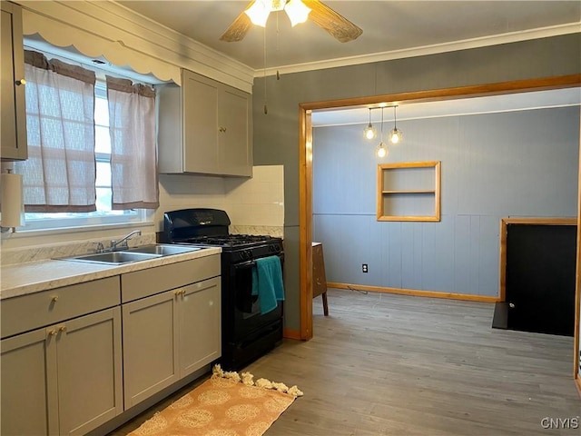 kitchen featuring ceiling fan, sink, black gas range oven, light hardwood / wood-style floors, and decorative light fixtures