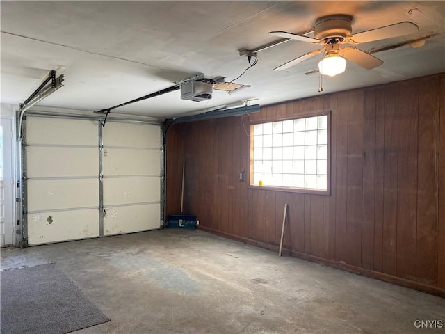 garage with ceiling fan, wood walls, and a garage door opener