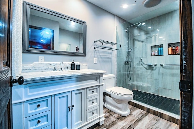 bathroom with a tile shower, vanity, and toilet