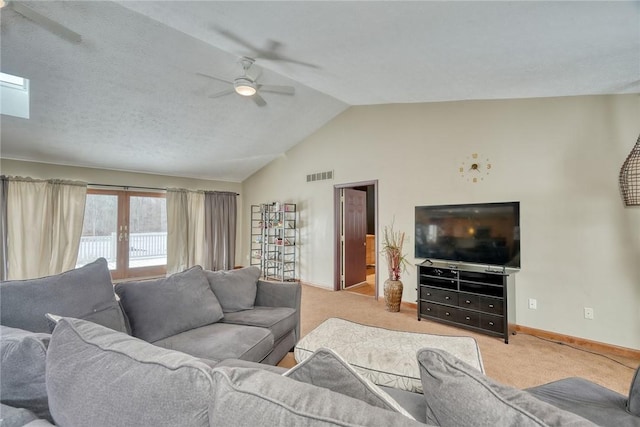 living room with french doors, ceiling fan, lofted ceiling with skylight, and light carpet