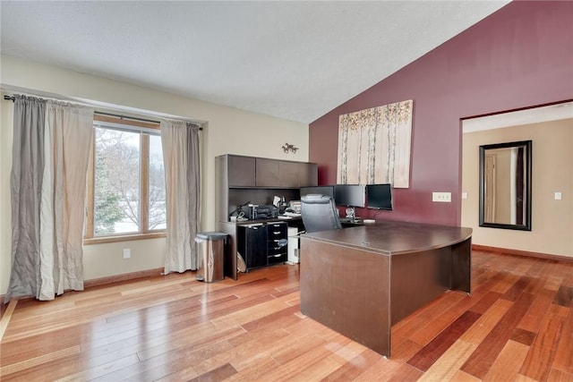 home office with light wood-type flooring and lofted ceiling