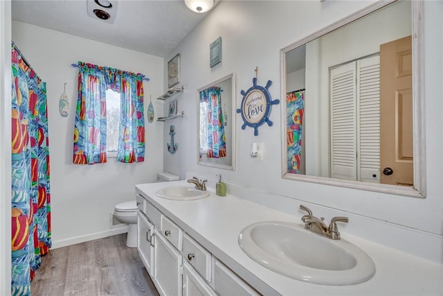 bathroom with toilet, wood-type flooring, vanity, and a textured ceiling