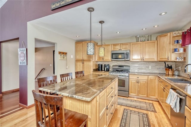 kitchen featuring a breakfast bar area, light hardwood / wood-style floors, stainless steel appliances, pendant lighting, and a kitchen island