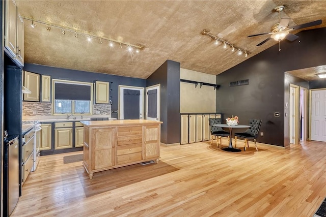 kitchen featuring vaulted ceiling, light hardwood / wood-style floors, backsplash, ceiling fan, and light brown cabinets