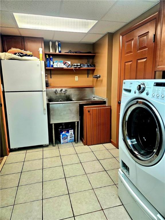 washroom with washer / dryer, light tile patterned flooring, and cabinets