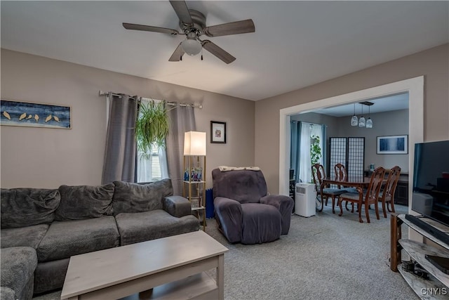 carpeted living room with ceiling fan with notable chandelier