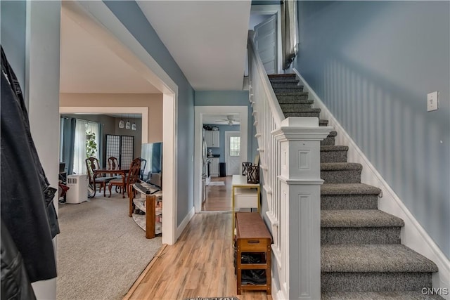 stairway featuring hardwood / wood-style floors, ceiling fan, and a healthy amount of sunlight