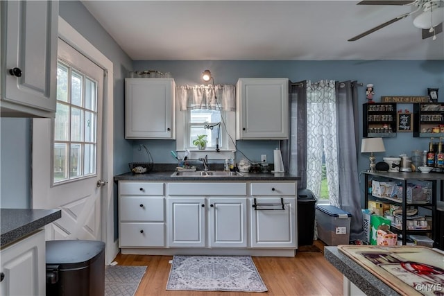 kitchen featuring white cabinets, light wood-type flooring, plenty of natural light, and sink