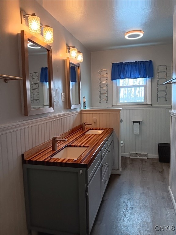 bathroom with toilet, wood walls, wood-type flooring, and vanity