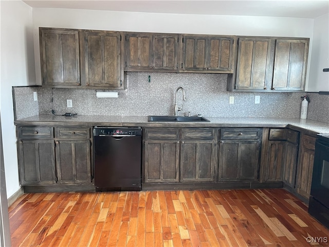 kitchen featuring tasteful backsplash, light hardwood / wood-style flooring, black dishwasher, and sink