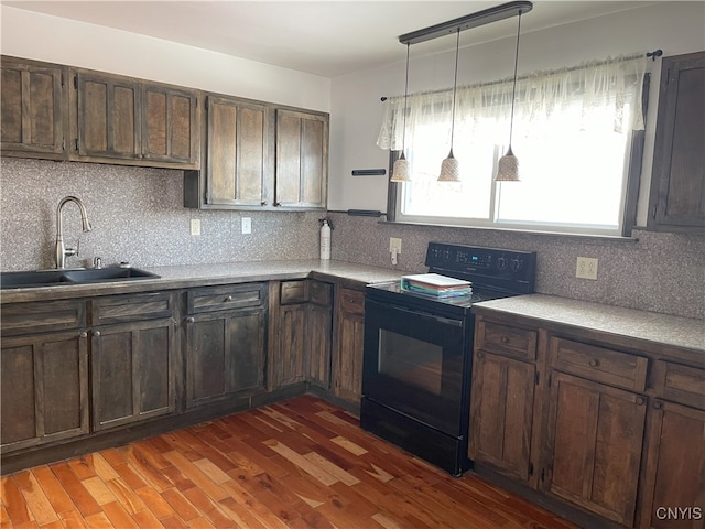 kitchen with black electric range, pendant lighting, dark wood-type flooring, sink, and tasteful backsplash