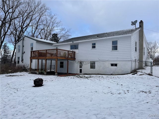 snow covered back of property featuring an outdoor fire pit and a deck