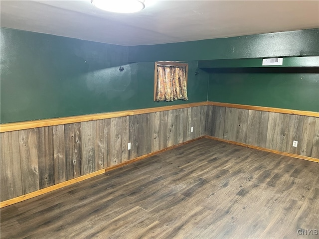 basement featuring dark wood-type flooring and wood walls