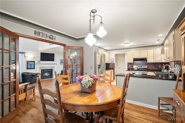 dining area with crown molding, sink, french doors, and light hardwood / wood-style flooring