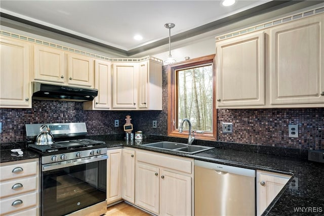 kitchen with appliances with stainless steel finishes, tasteful backsplash, sink, decorative light fixtures, and dark stone countertops