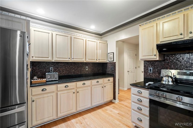 kitchen featuring light wood-type flooring, stainless steel appliances, dark stone counters, and tasteful backsplash