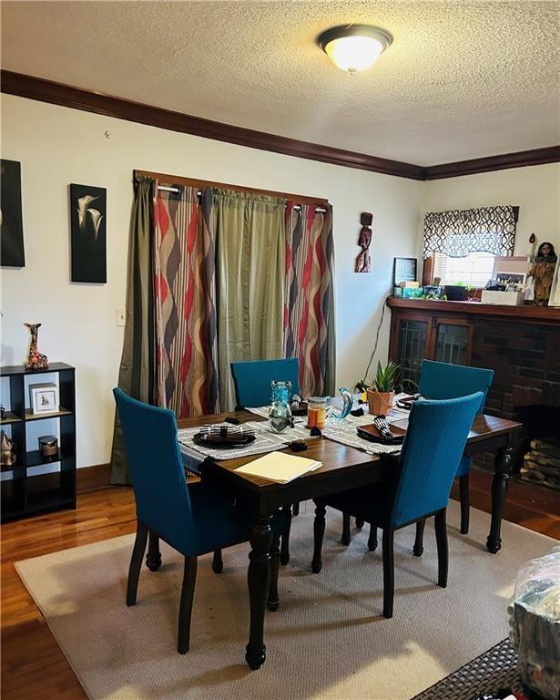 dining space with hardwood / wood-style flooring, crown molding, and a textured ceiling