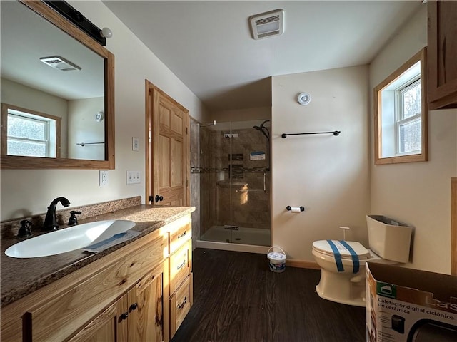 bathroom featuring toilet, hardwood / wood-style floors, vanity, and tiled shower