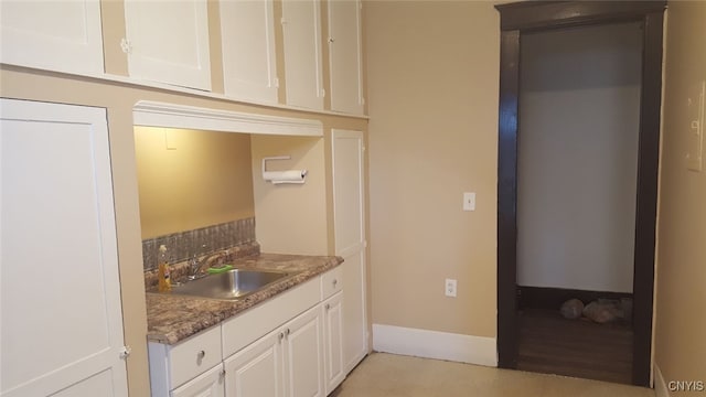 kitchen featuring white cabinetry, dark stone counters, and sink