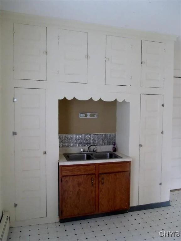 kitchen with backsplash, baseboard heating, and sink