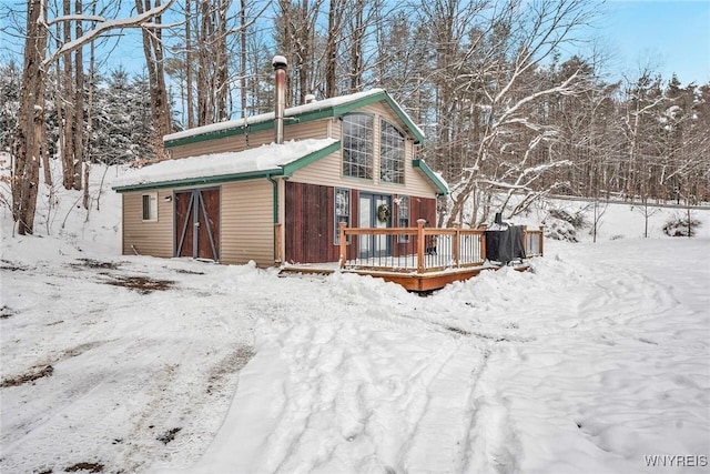 snow covered back of property featuring a deck