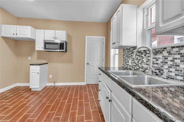 kitchen featuring decorative backsplash, sink, white cabinets, and hardwood / wood-style flooring